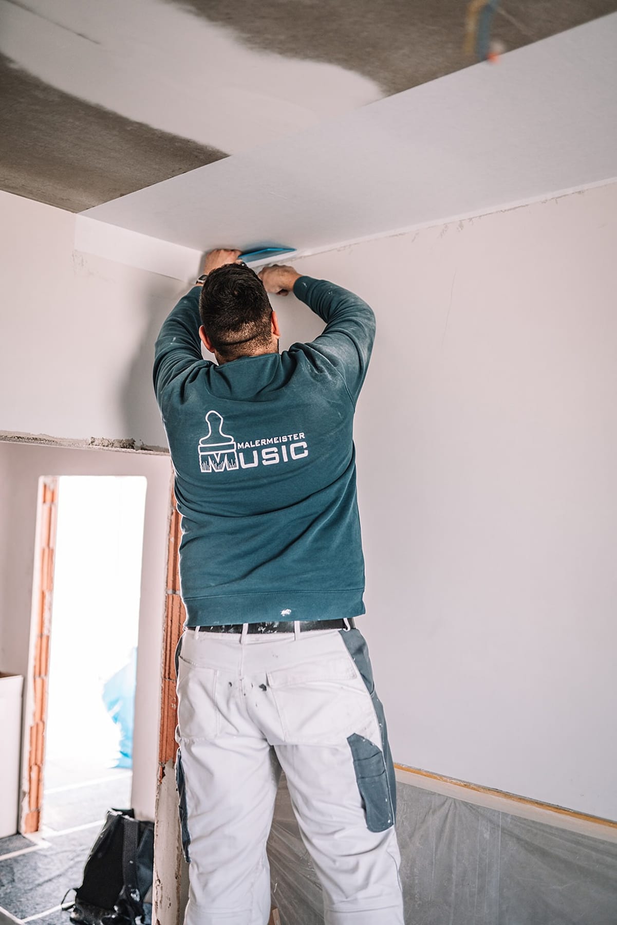 Malermeister bei Streicharbeiten an der Decke